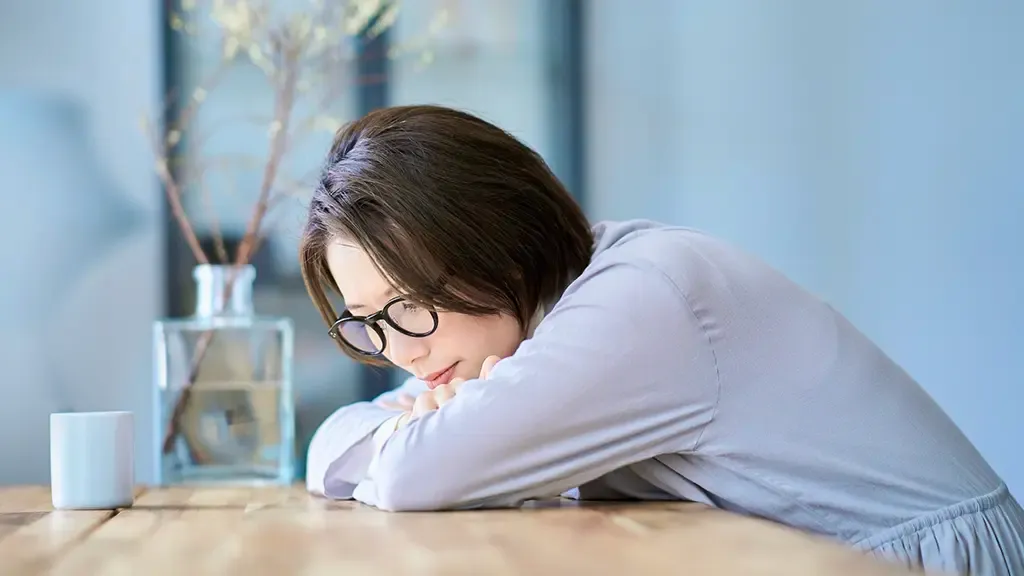 疲れを感じて机にうつ伏せになっている